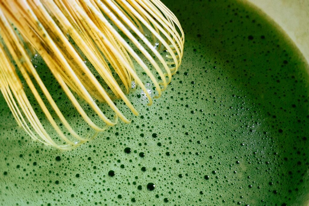 泡立てた抹茶を茶筅ですくう様子