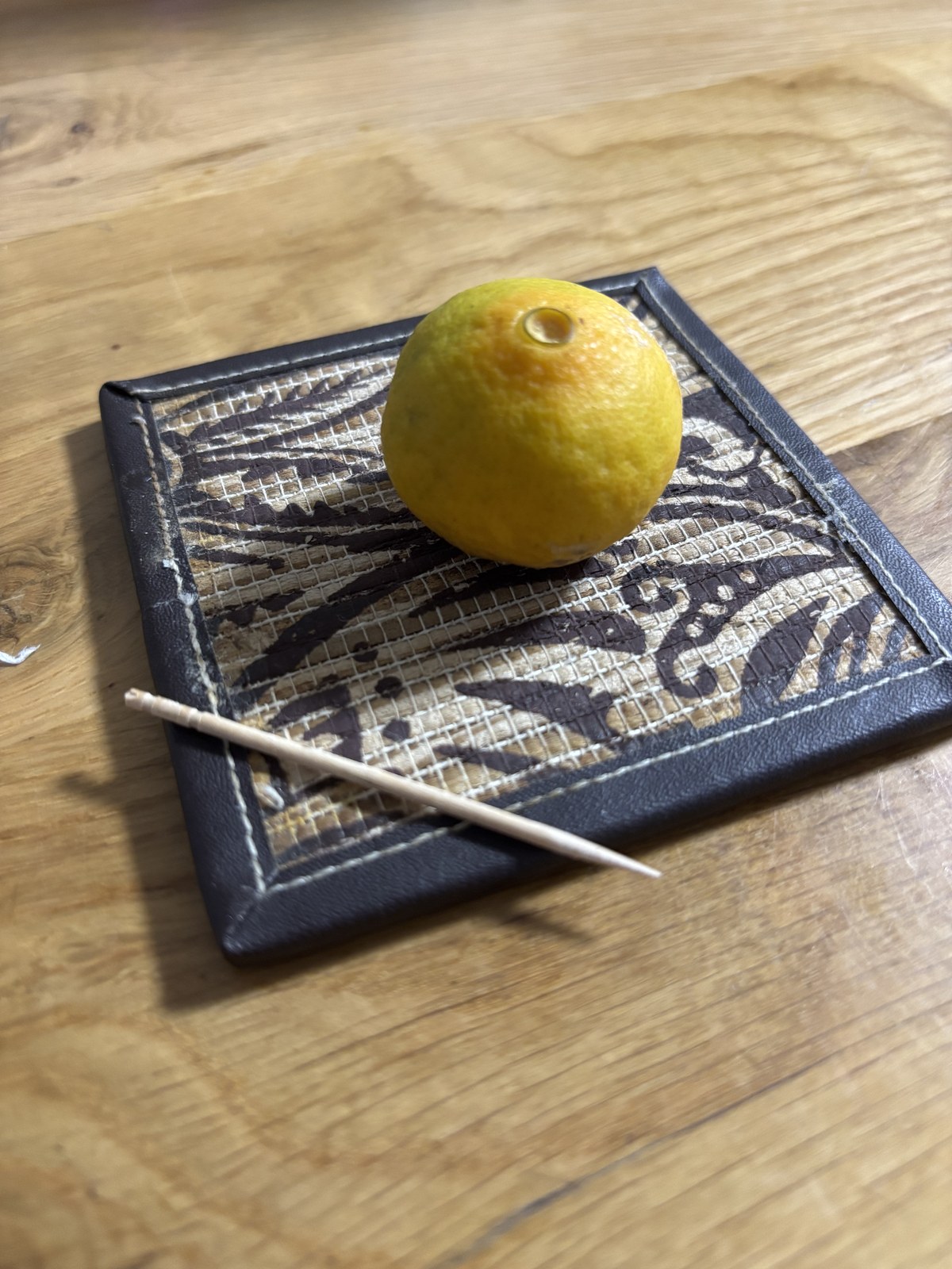 落ちたみかんをコースターに乗せて飾ったところ。和菓子に見立てて菓子楊枝を添えてある